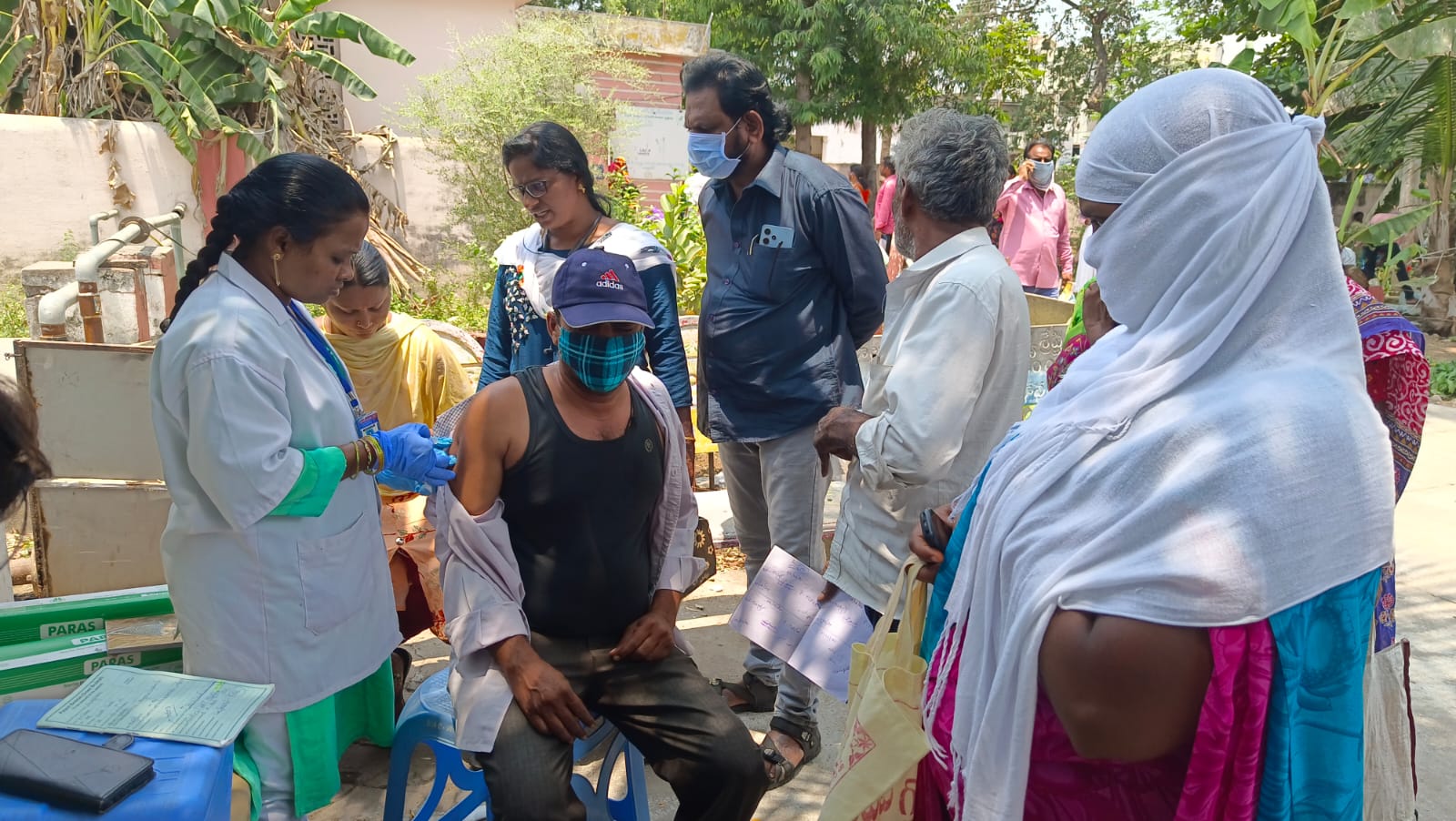 Healthcare worker administering vaccination to man during community health camp