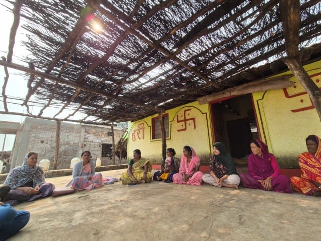 A group of rural women having a meeting in front of a house in the front yard