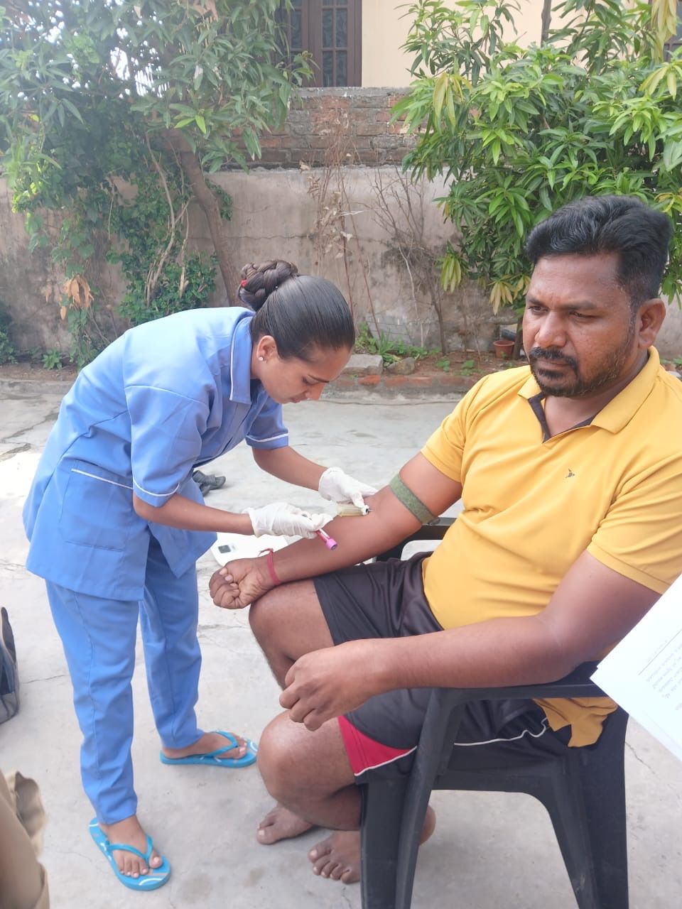 Healthcare worker collecting blood sample from man during home visit