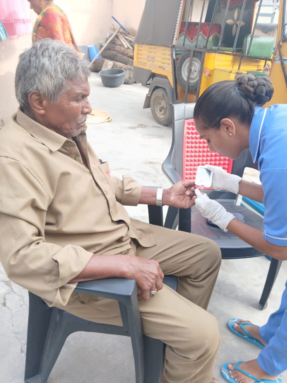 A health worker collecting a blood sample from an elderly man.