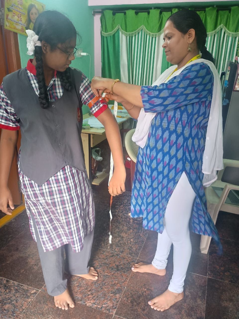 Healthcare worker measuring arm circumference of student for nutritional assessment