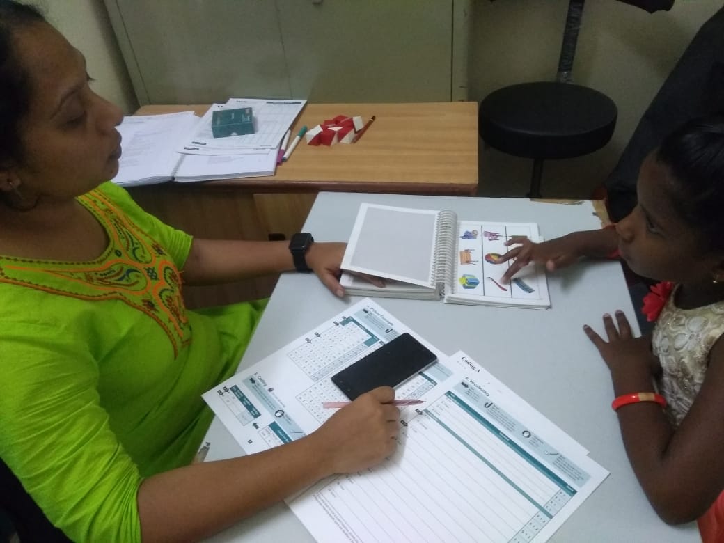 Healthcare worker conducting developmental assessment with child using visual charts