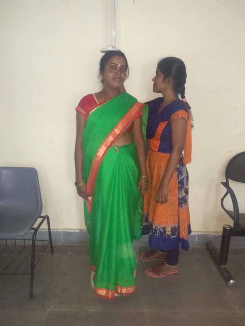 A health worker is measuring a woman’s height
