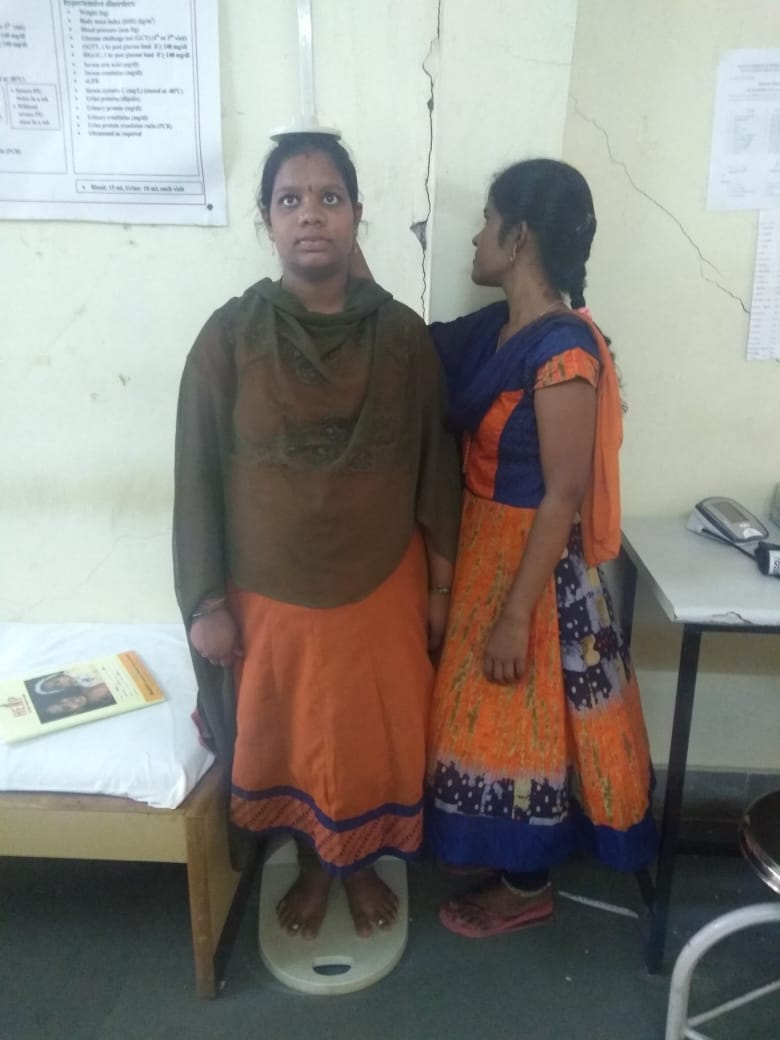 A health worker measuring the height of a lady