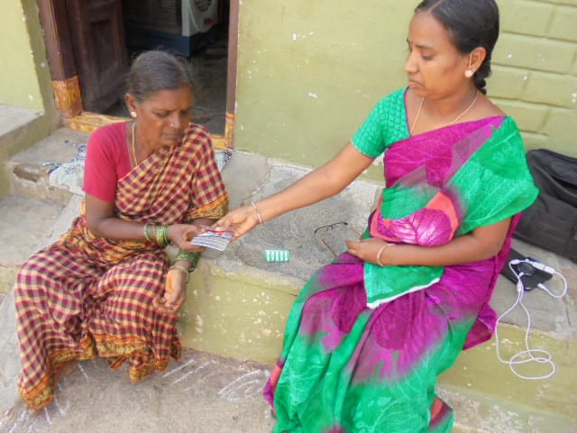 A health worker giving medicine to a rural old lady