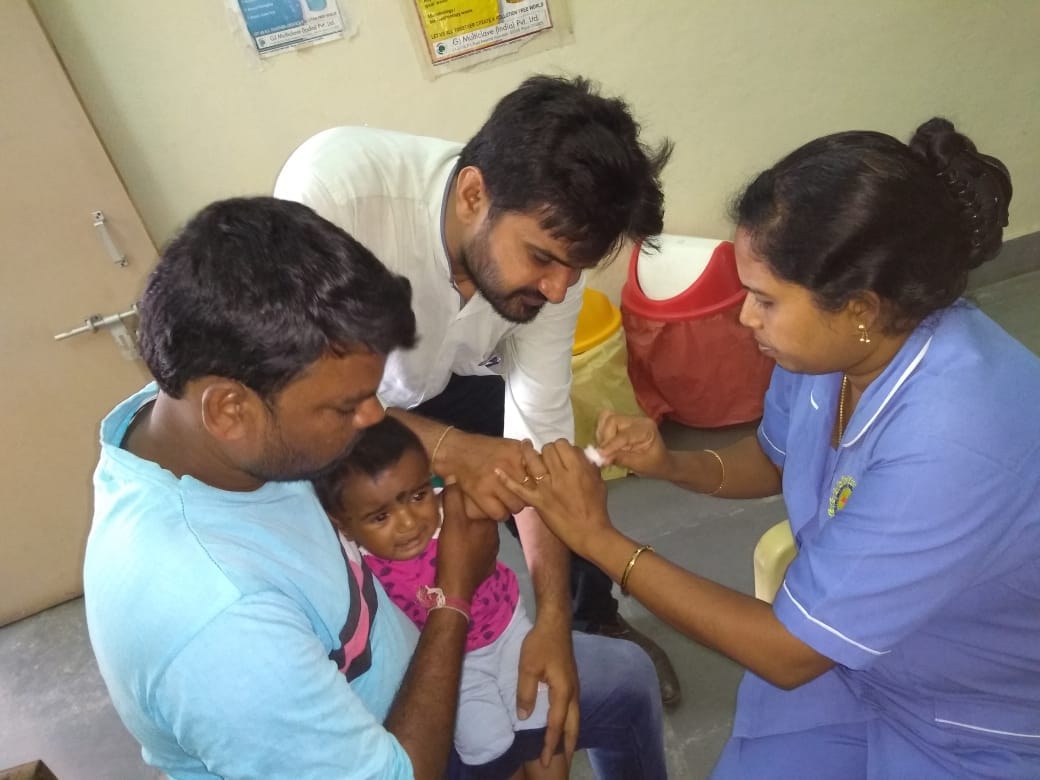 Infant receiving vaccination injection with healthcare worker while parent holds child