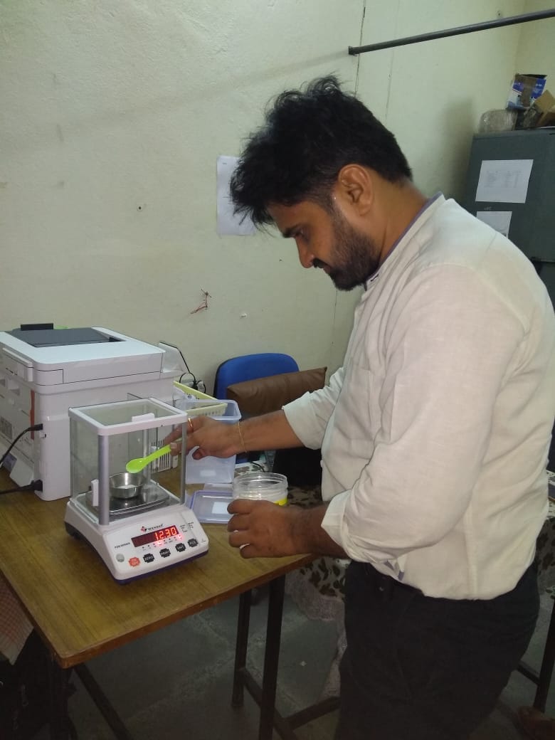 Lab technician measuring sample on digital weighing scale in laboratory