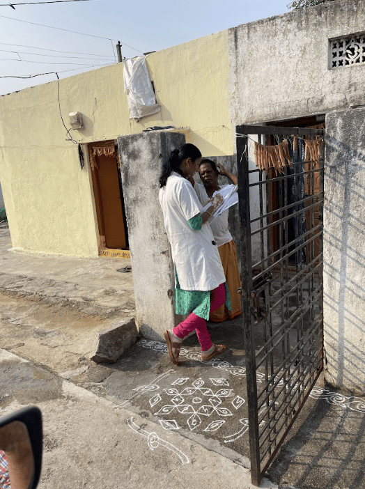 Healthcare worker conducting door-to-door survey and recording information outside house