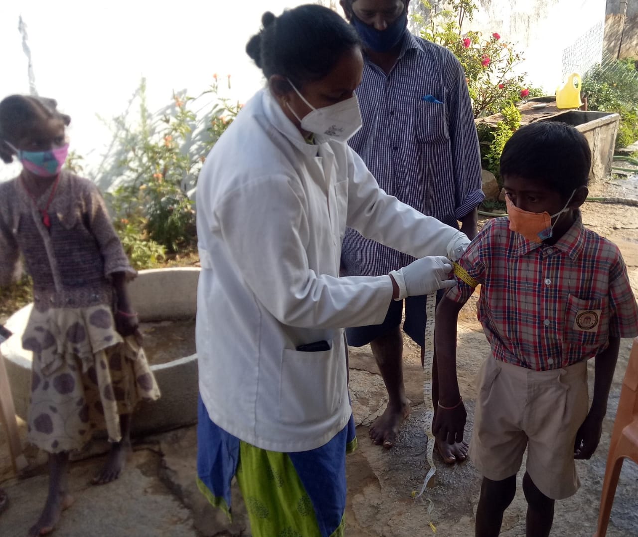 A health worker measuring the arms of a schoolboy