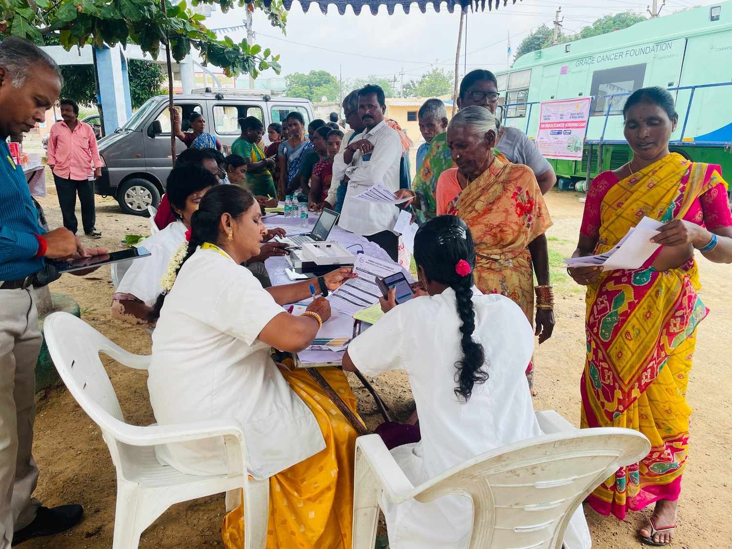 “Community health camp registration and screening activity with healthcare workers assisting villagers at an outreach site
