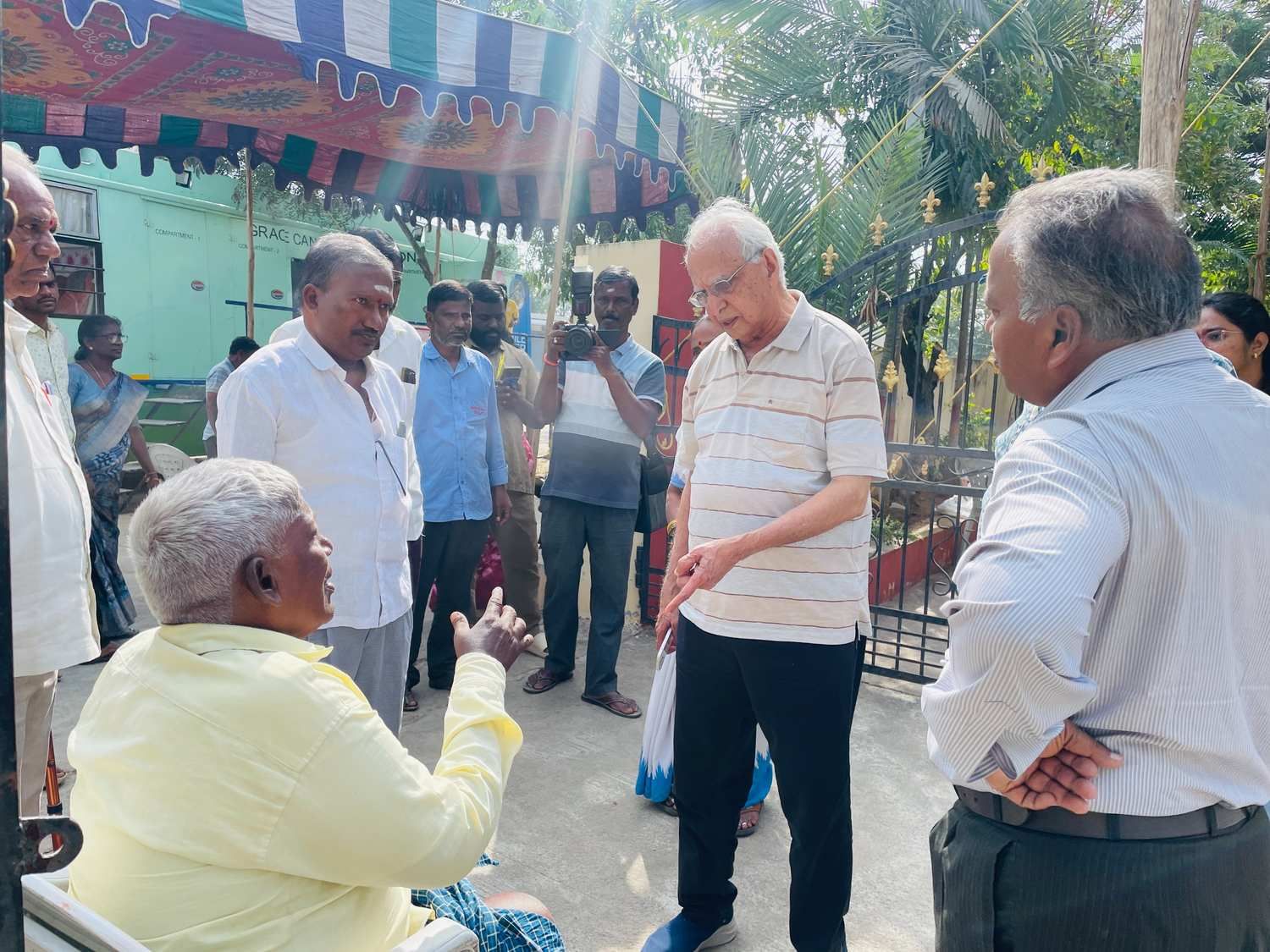 Senior professionals interacting with a community member during a visit to a medical camp site, discussing concerns and outreach activities
