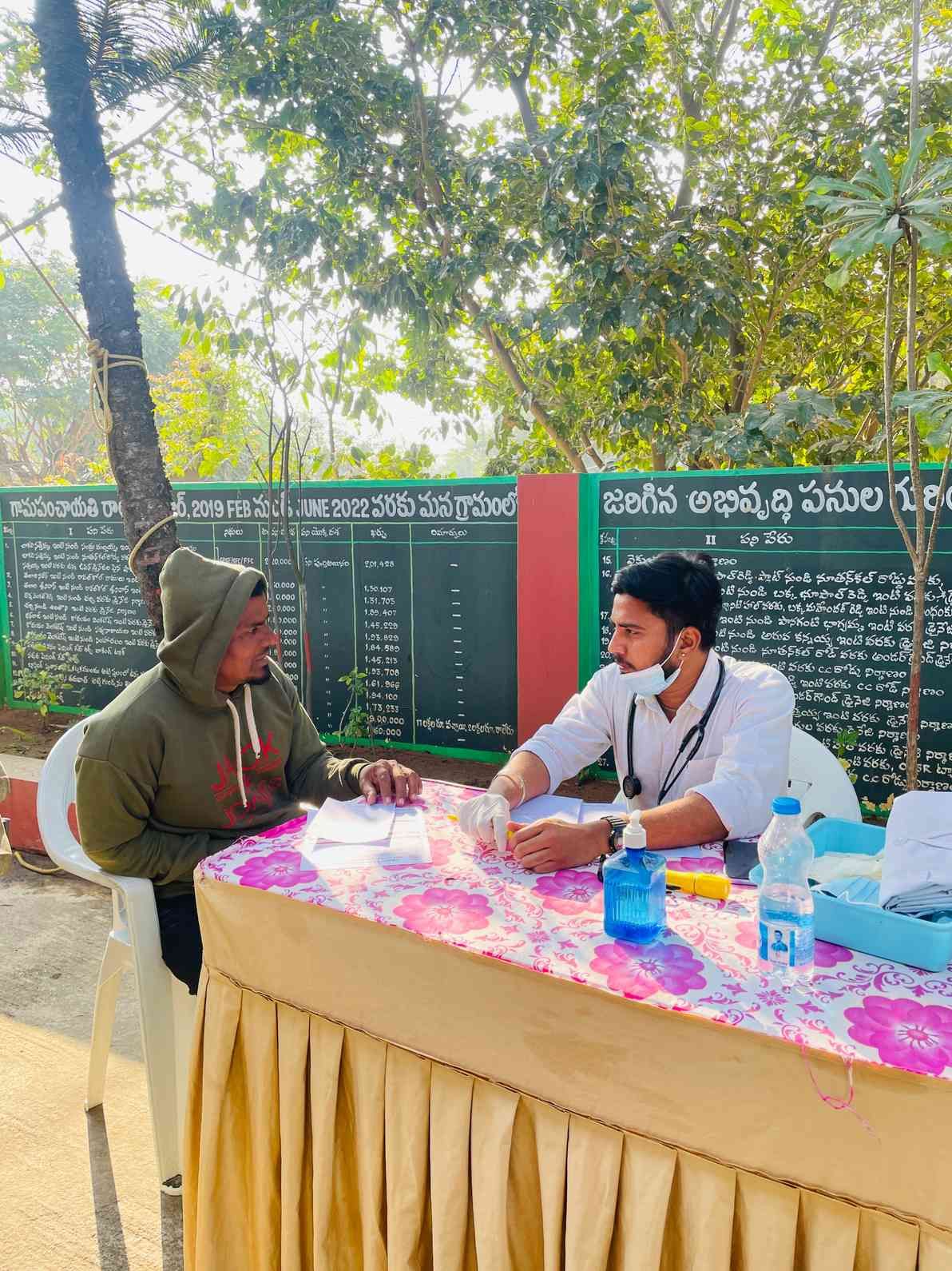 Doctor consulting a patient and conducting a basic health screening during an outdoor community medical camp