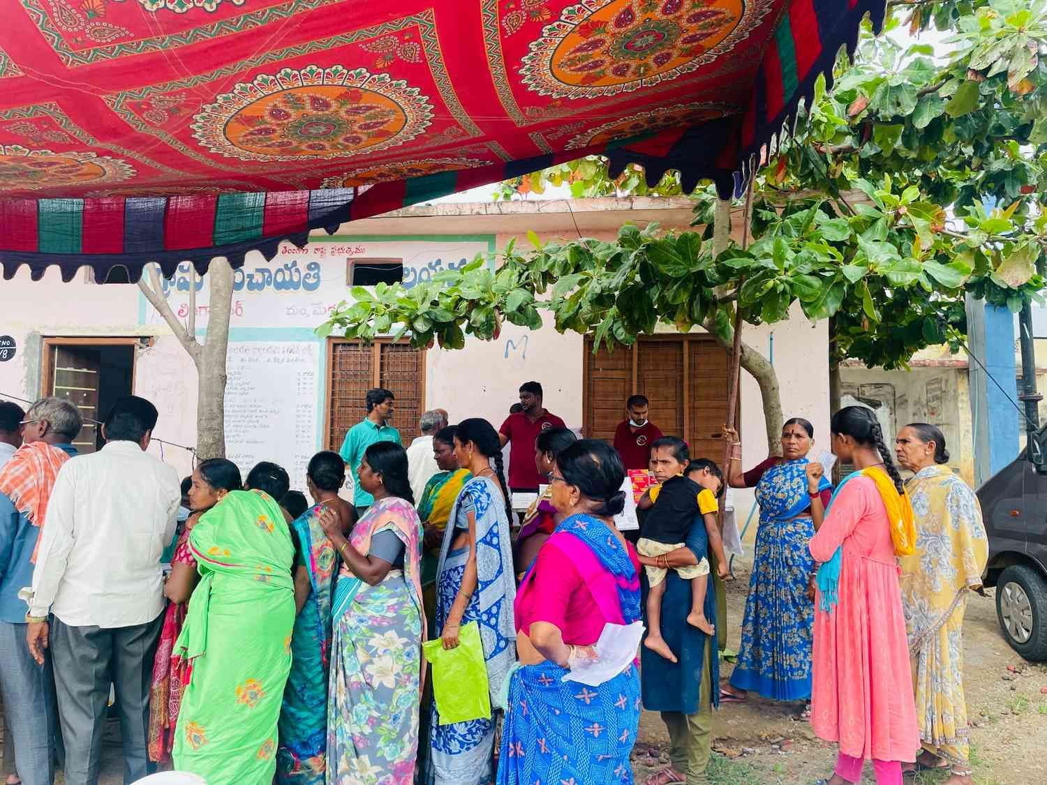 Community members standing in queue at medical camp registration area