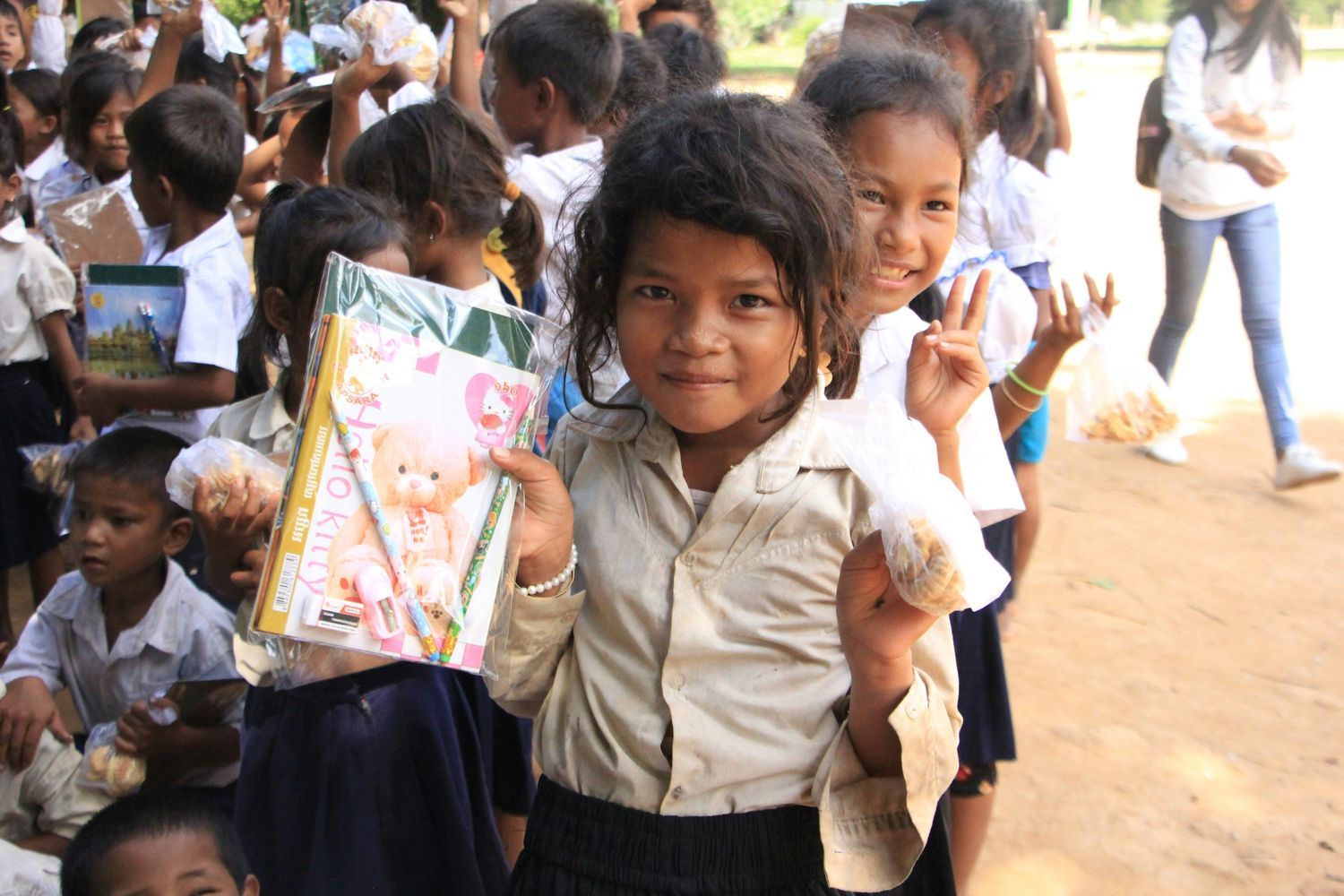 School children holding books and snacks while smiling during distribution activity