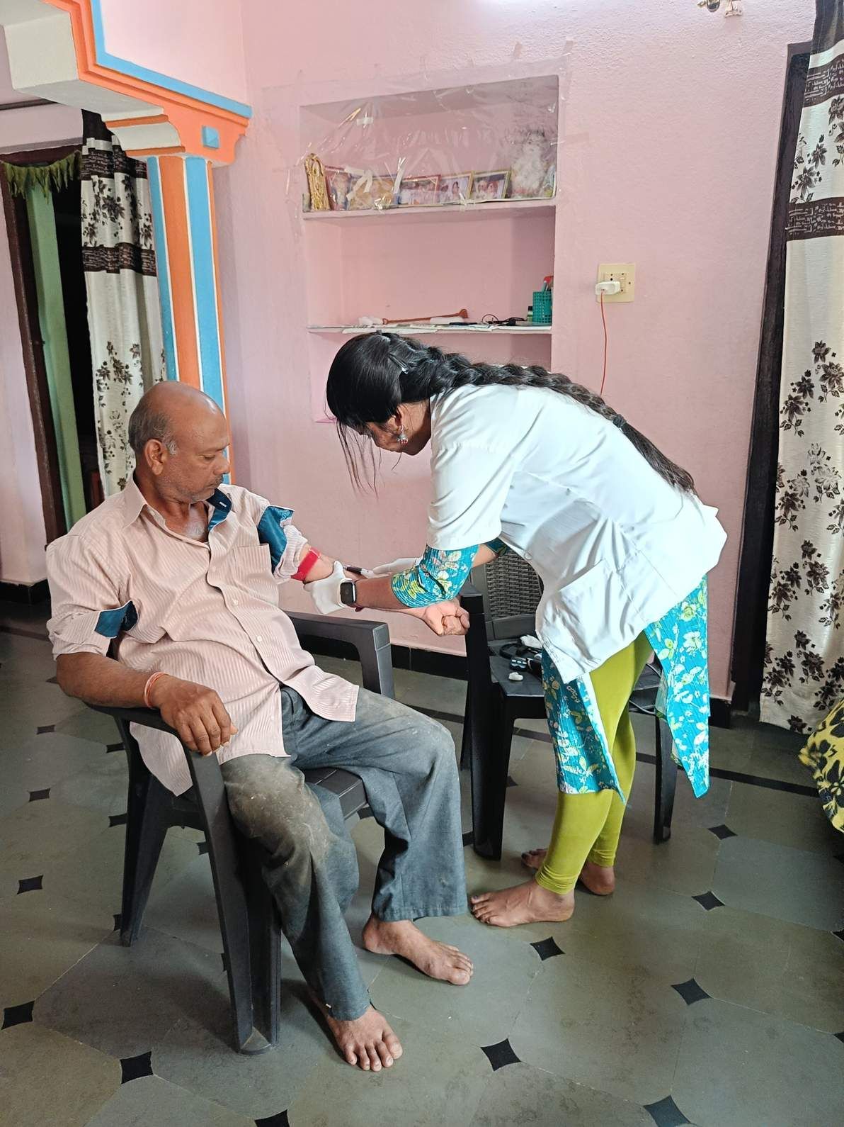 Healthcare worker measuring blood pressure of man during home visit