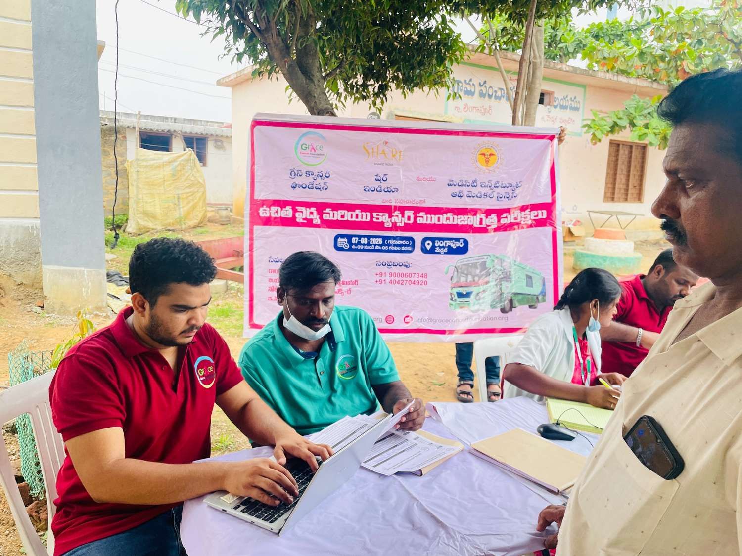 Healthcare staff registering a patient and managing records at a community medical camp registration desk