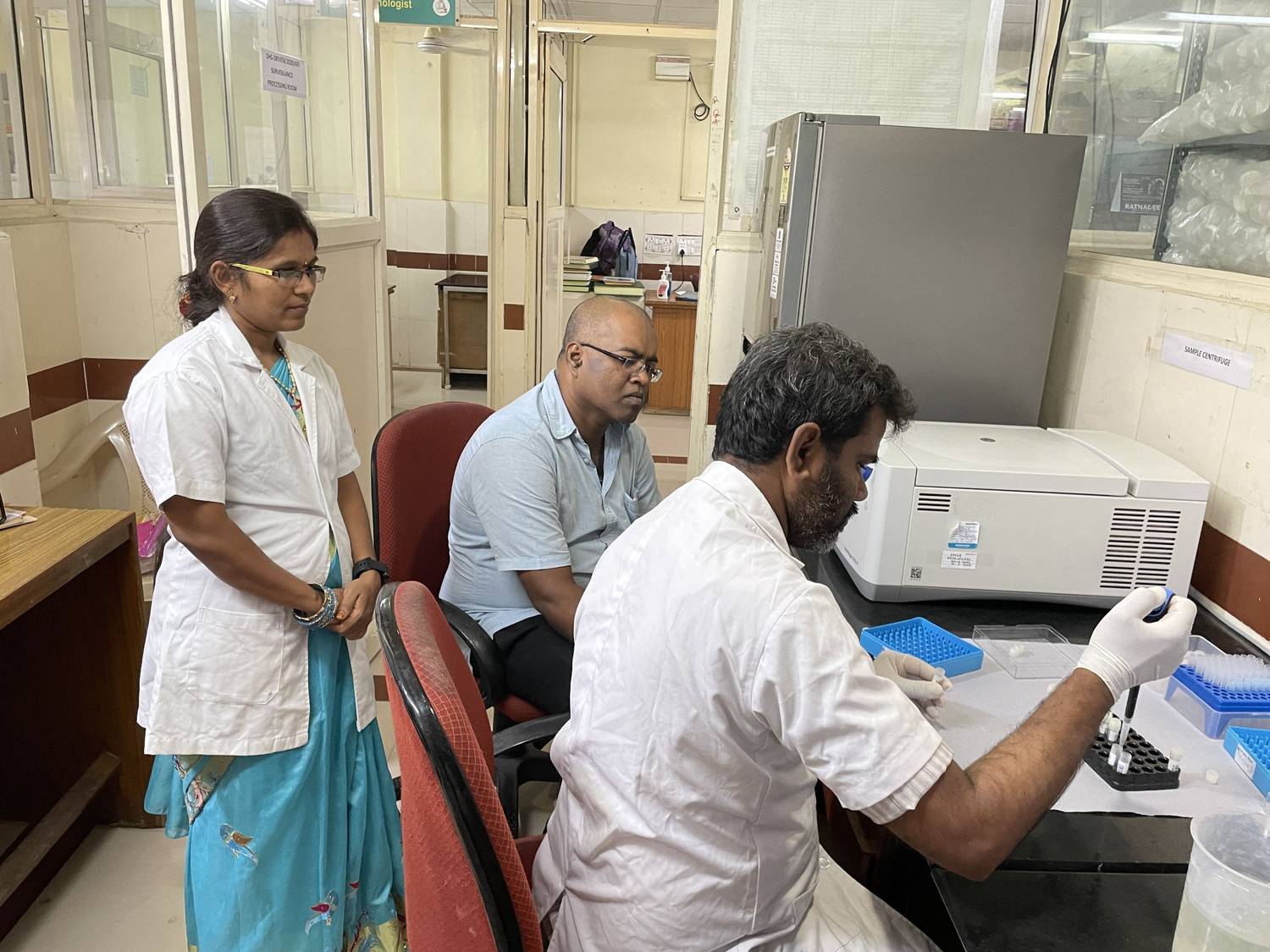 Laboratory technician conducting sample testing while team observes in lab