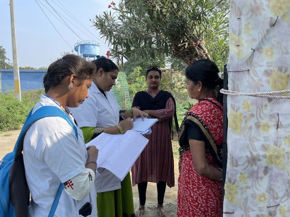 Community health workers conducting a household survey and interacting with a rural woman outdoors
