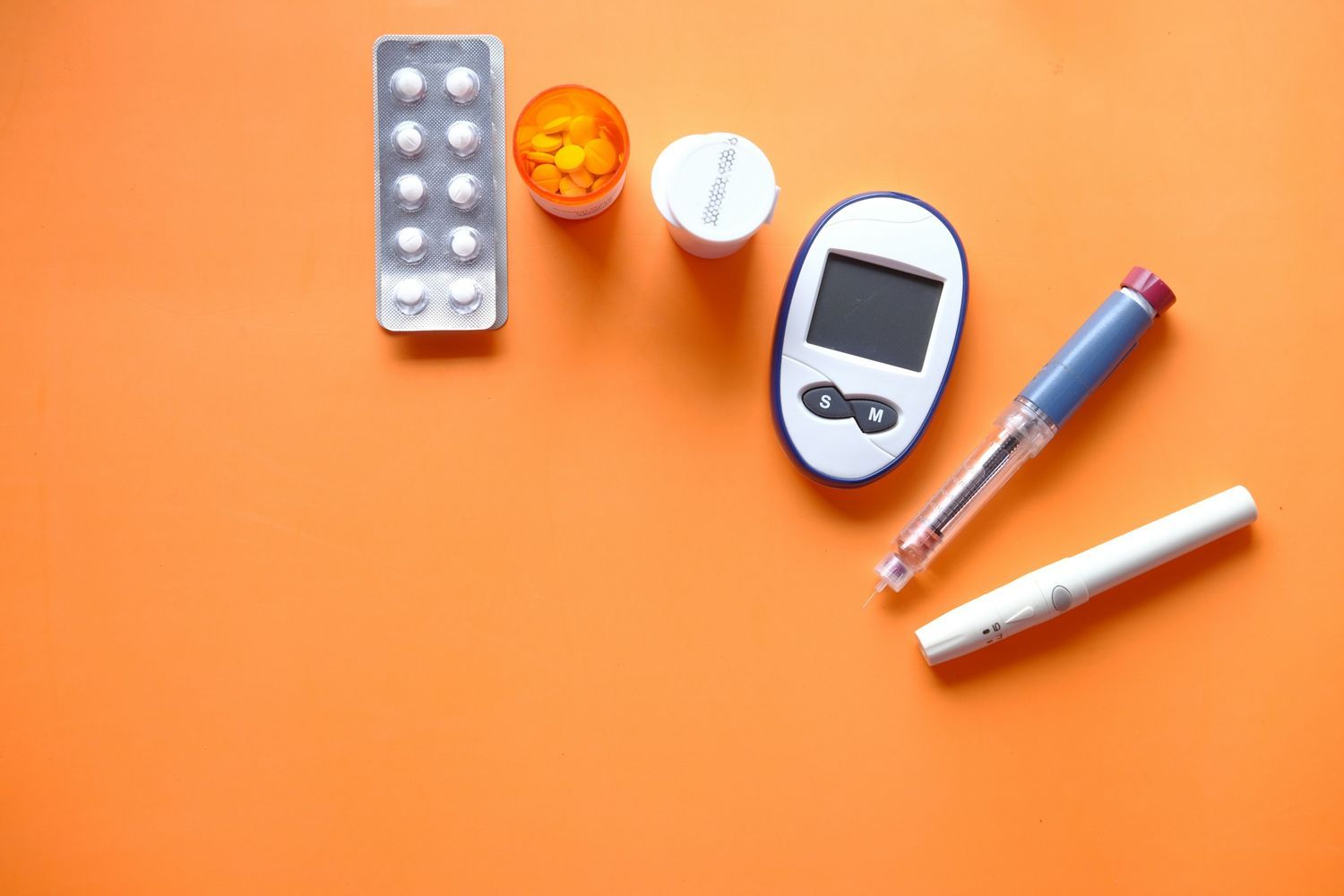 Diabetes management tools including glucose meter, insulin pen, syringe, and medication pills on orange background