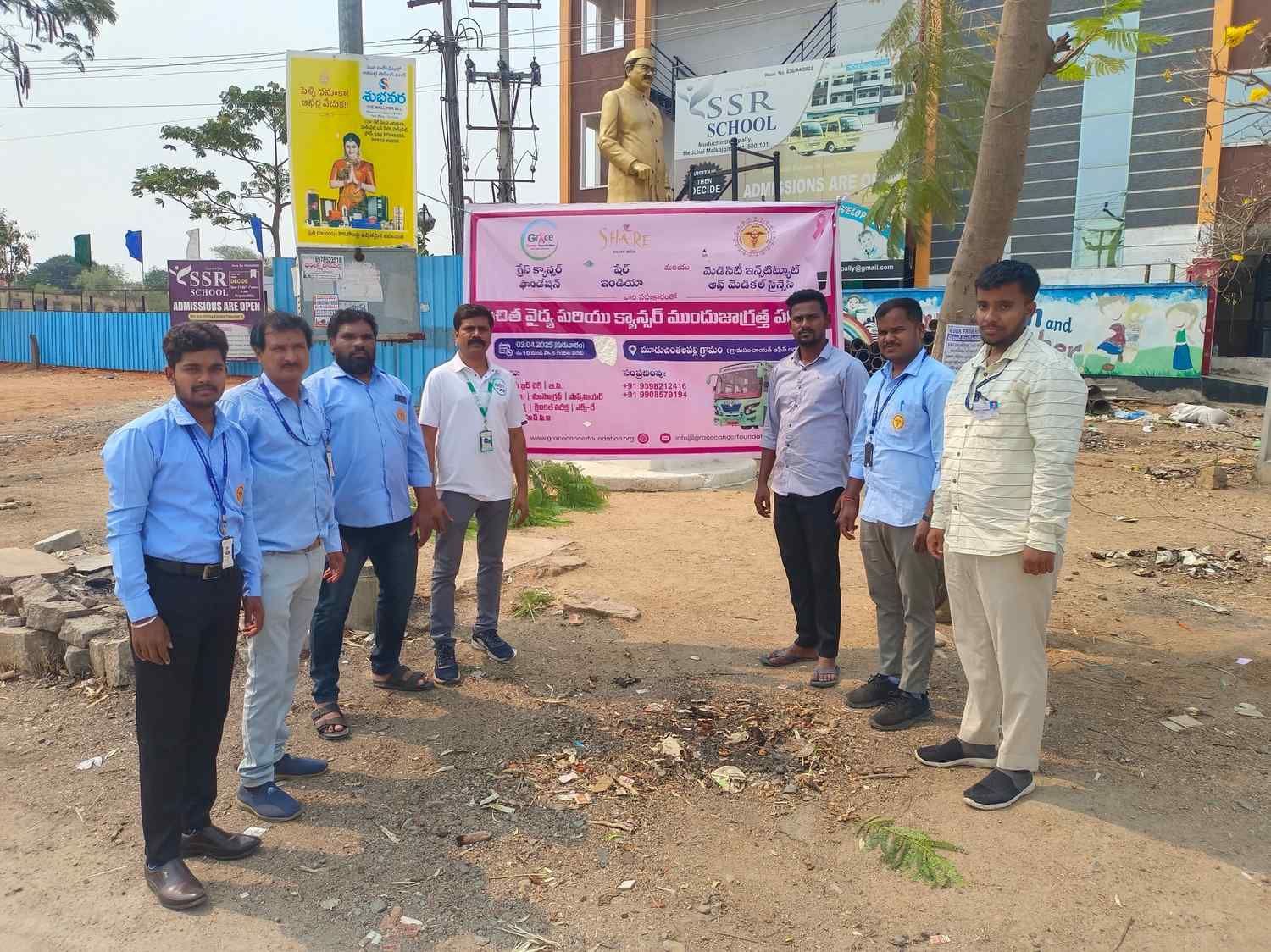 Team members standing near awareness banner during community outreach activity