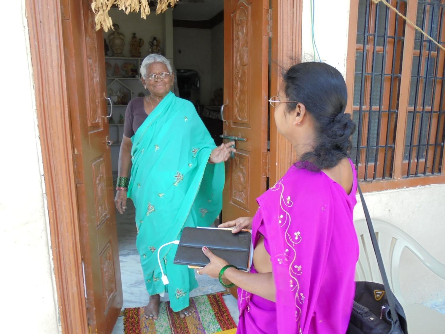Community health worker conducting a doorstep visit and interacting with an elderly woman at her home