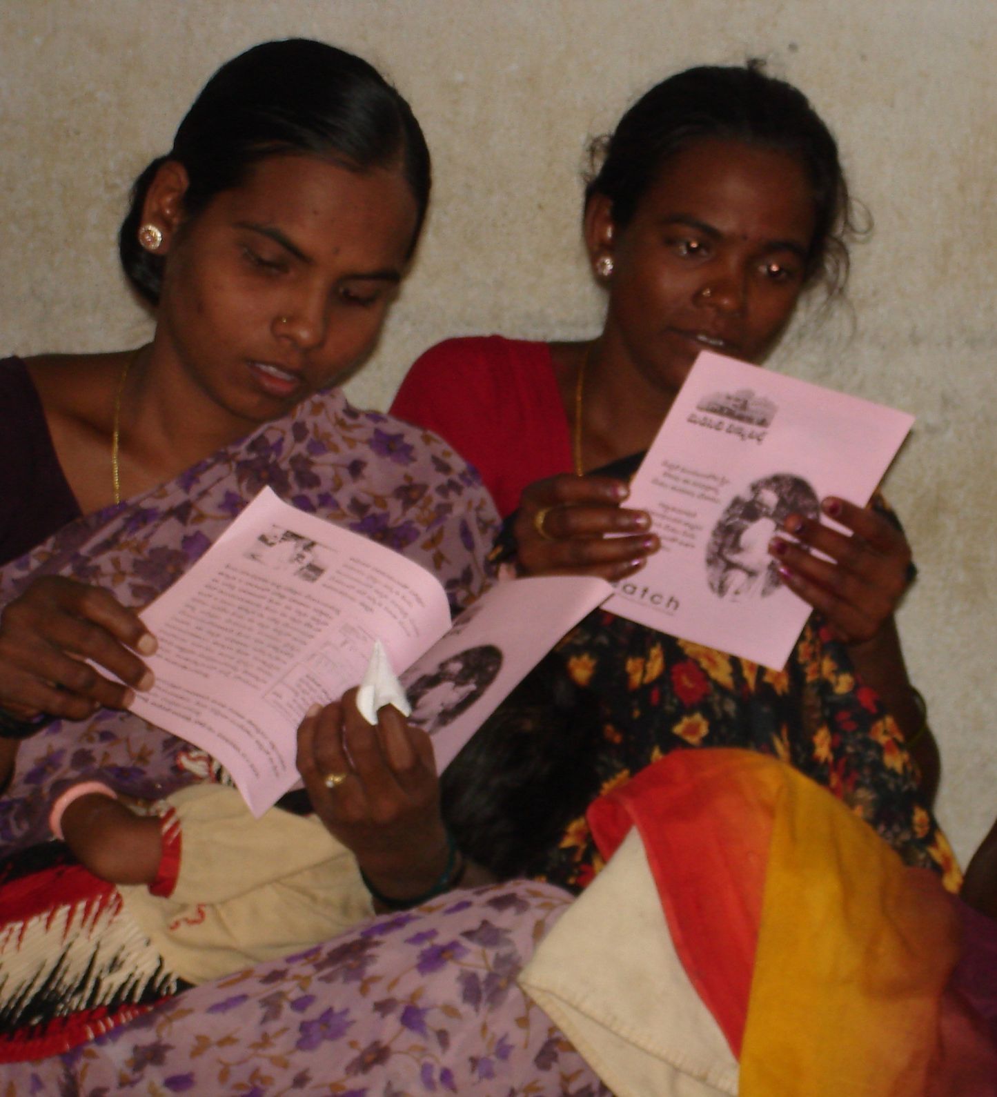 Two women reading informational pamphlets, likely related to health awareness or education.