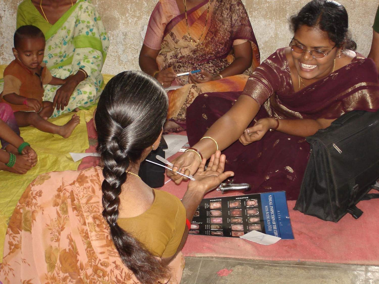 Healthcare worker conducting finger prick blood test for woman during community screening