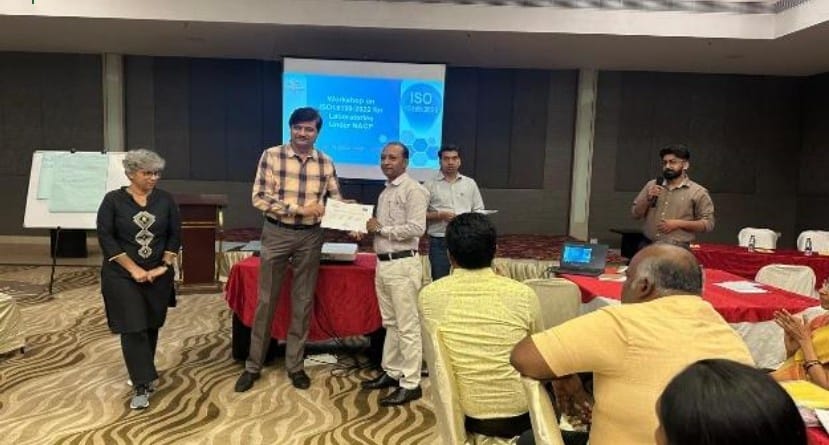 Certificate distribution during a professional training workshop, with participants and facilitators gathered in a conference setting
