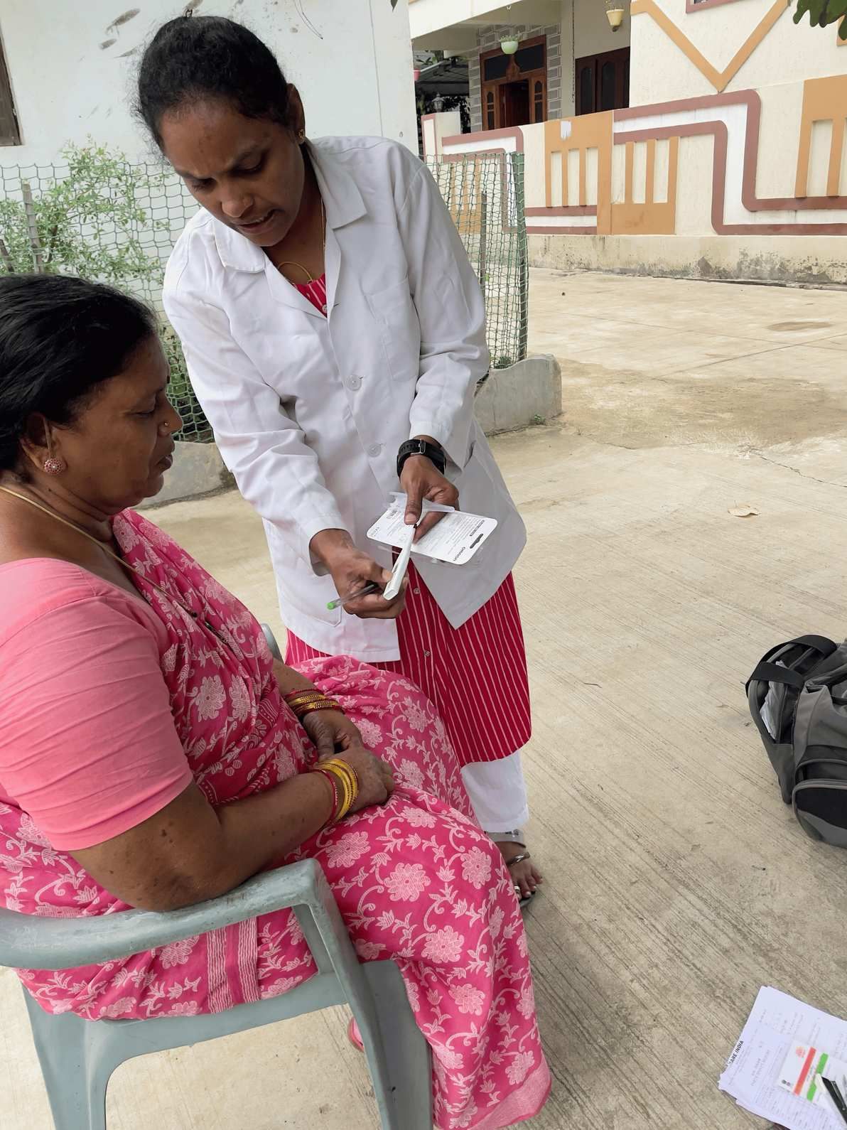 Community health worker providing on-site diagnostic screening and guidance to a woman during a field visit