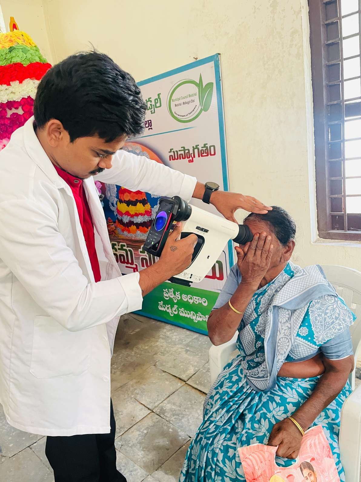 Healthcare professional conducting eye screening of an elderly woman using diagnostic device at medical camp