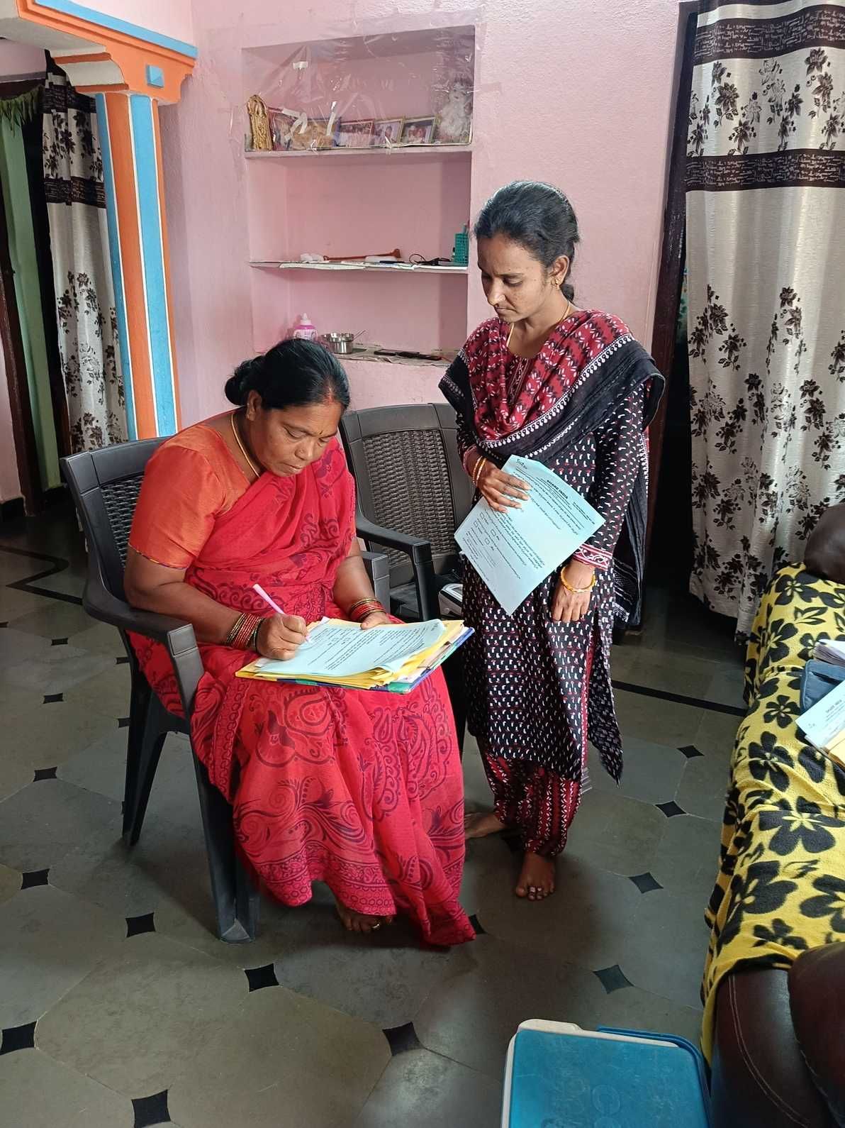 Community health worker completing documentation while conducting a household visit with a beneficiary in a rural home