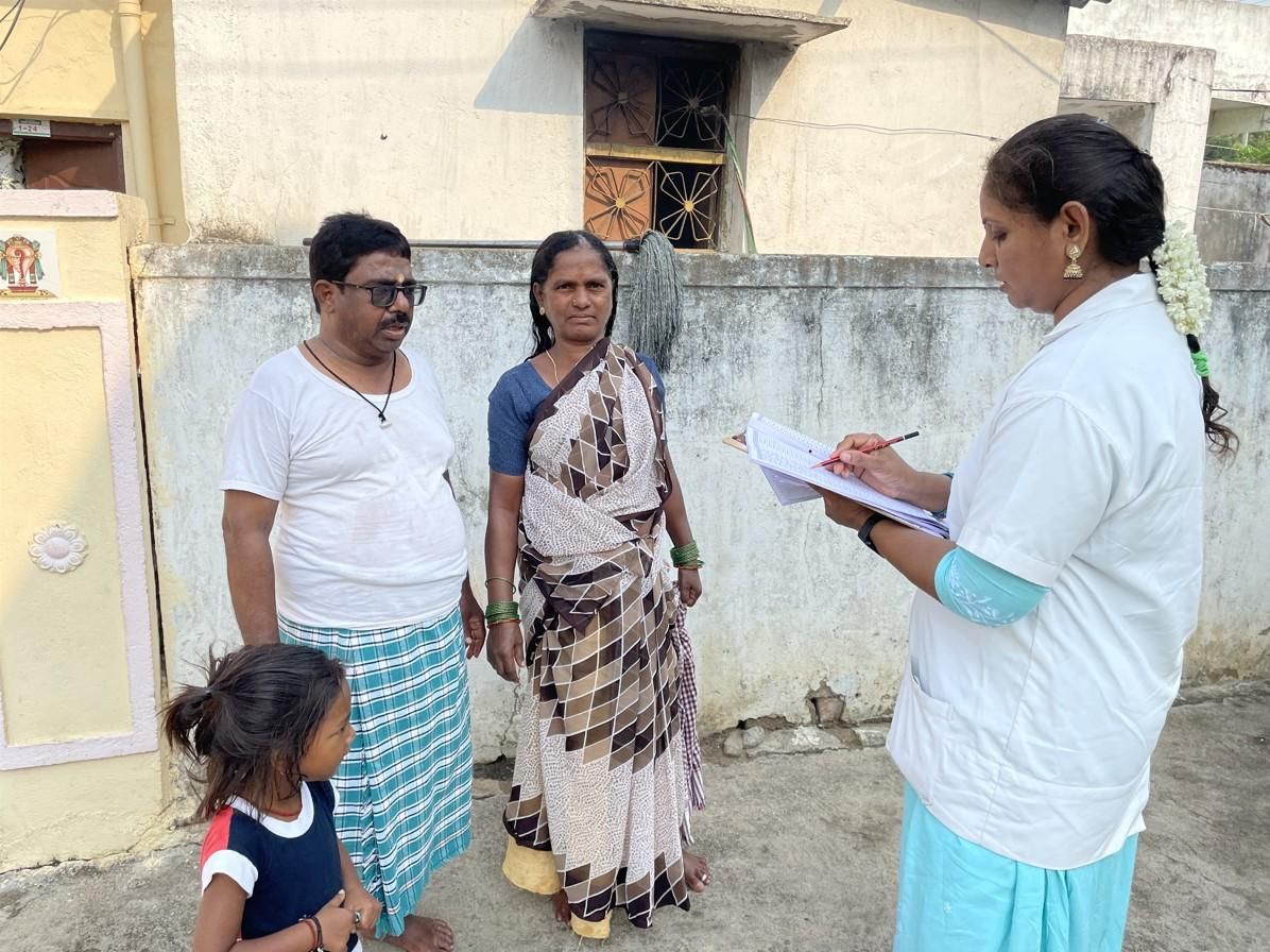 Community health worker collecting household health information from a family during a field survey visit