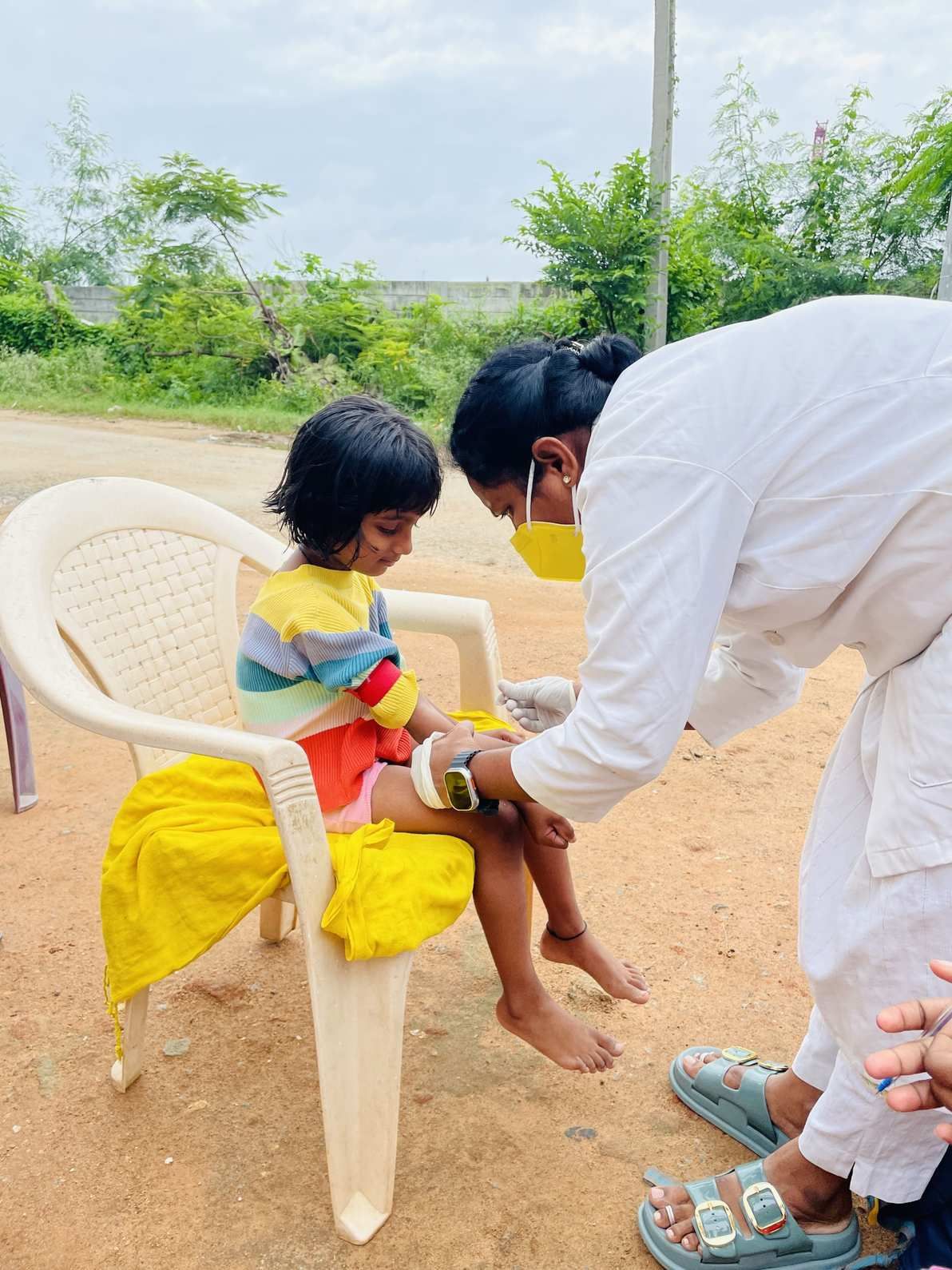 Healthcare worker collecting a blood sample from a child during an outdoor community health screening