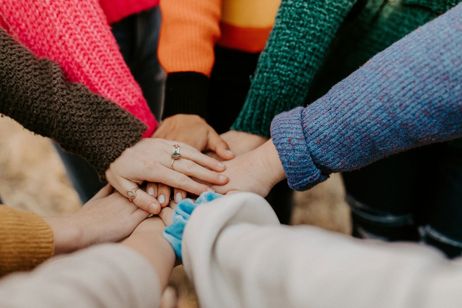 A group of people placing their hands together in a gesture of unity and teamwork.