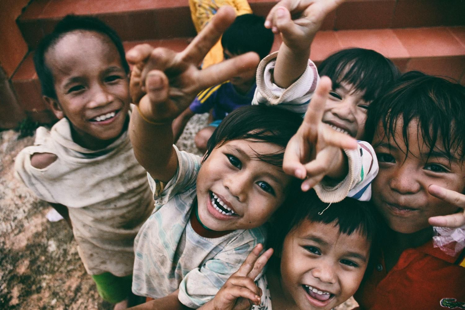 A group of happy children smiling and making peace signs toward the camera